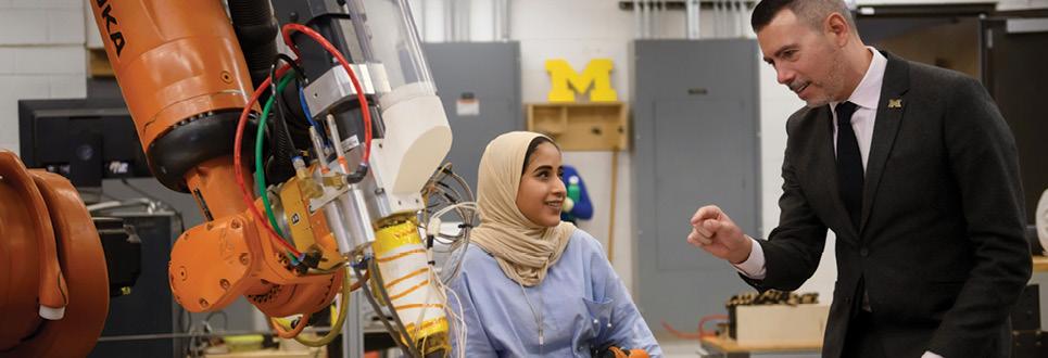 Professor referencing a 3-D printer as he speaks with female student in hijab