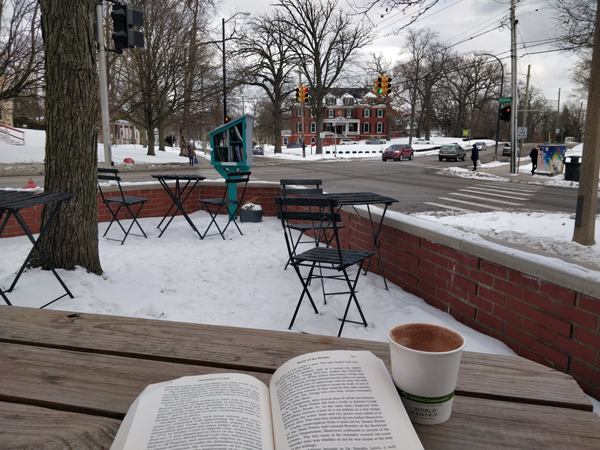 enjoying a cup of coffee and reading a book at outside cafe