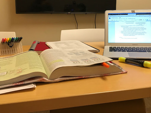 Textbooks and laptop spread out on a desk
