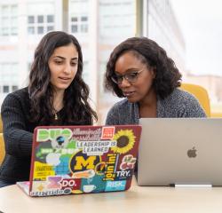 A student and a faculty member looking at laptops