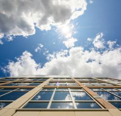 Looking up the side of a building with blue sky and clouds above