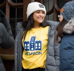 Woman student wearing a winter coat and hat and a University of Michigan t-shirt