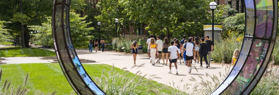 A group of students on campus seen through a sculpture