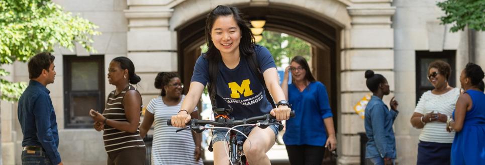 Student biking through the West Hall arch