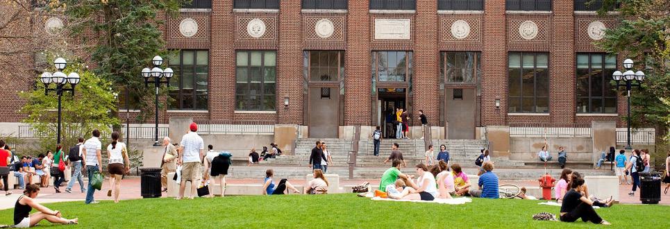 Students sit in the grass on the Diag in spring