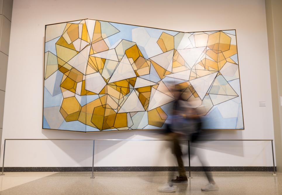 A student walking very fast past a large painting of geometric shapes